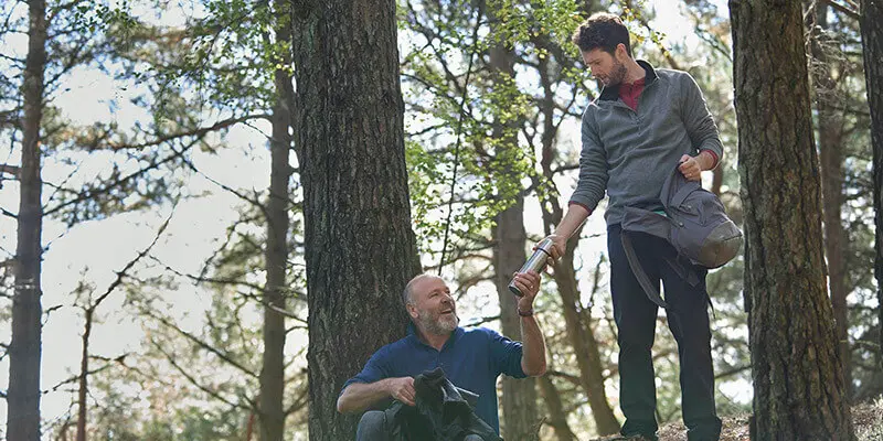 Two men drinking coffee in the woods